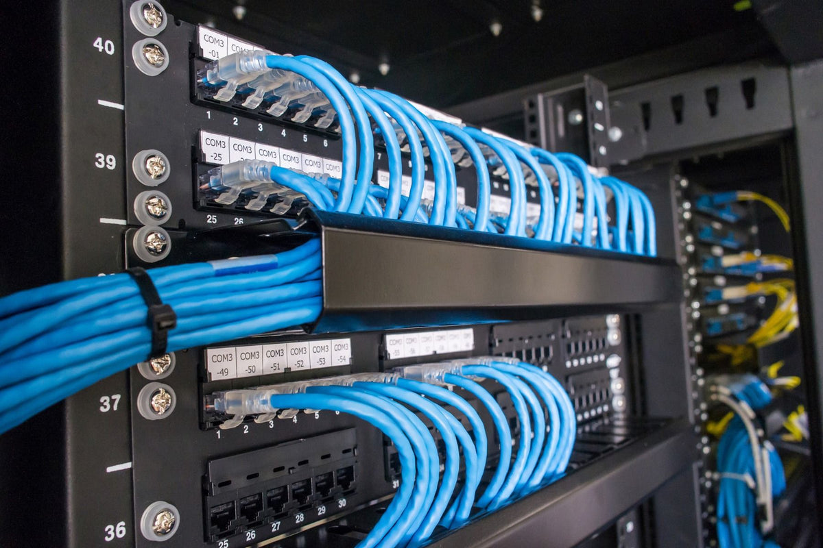 Network switch with blue patch cables in a server room setting