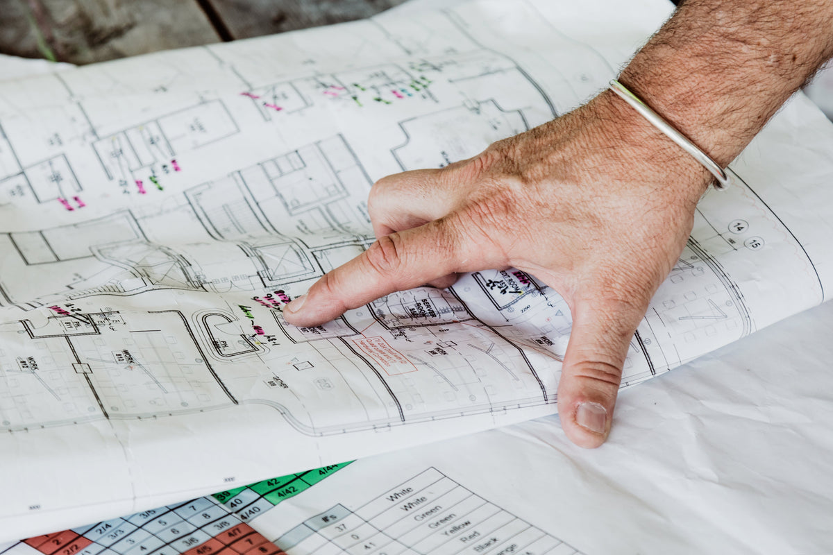 Hand pointing to blueprints on a table