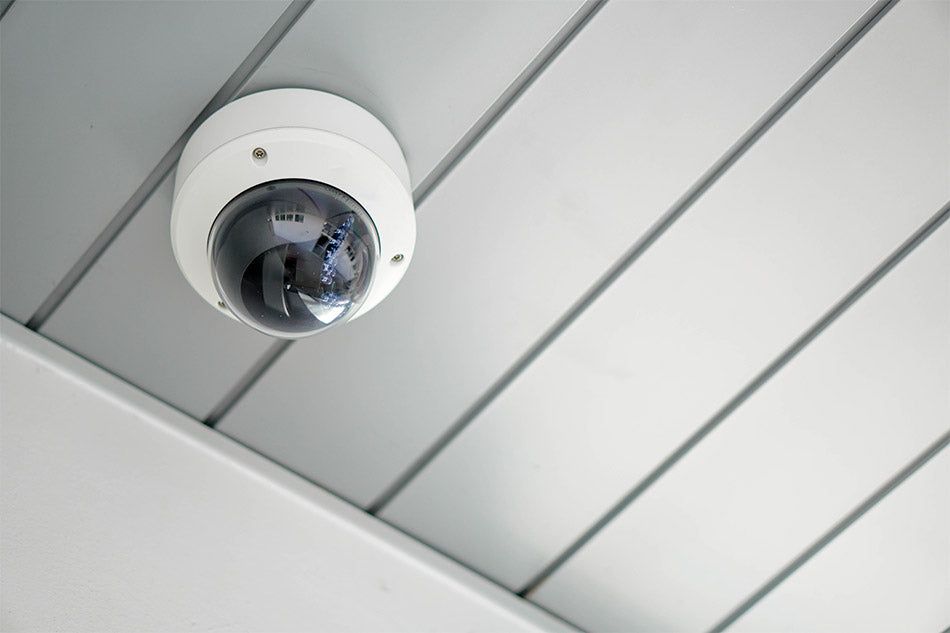 Security camera mounted outdoors on a gray ceiling.